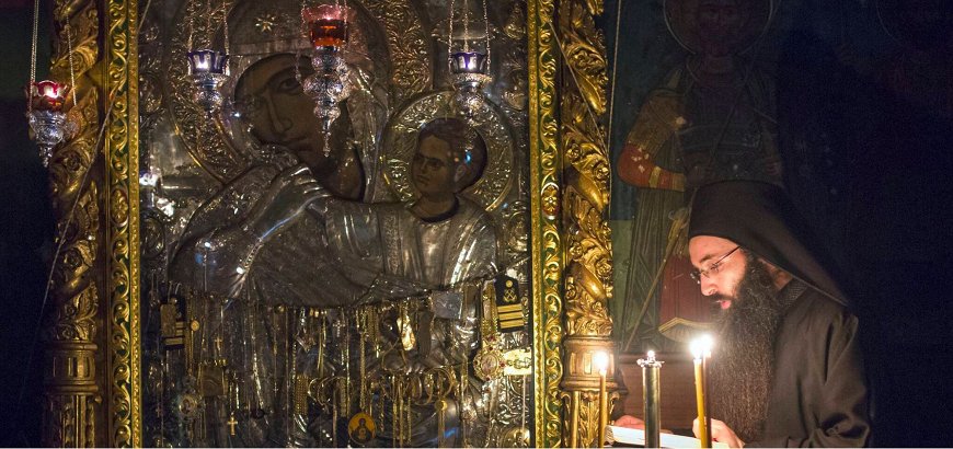Ένας μοναχός προσεύχεται μπροστά από την εικόνα της Παναγίας.